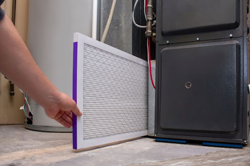 A person installing a new furnace air filter.